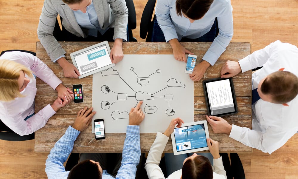 group of colleagues around a table using technology