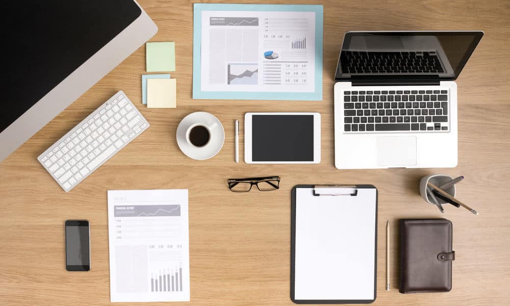 An organized office space with laptop, coffee, glasses, pencil case, and other supplies arranged neatly on a desk.