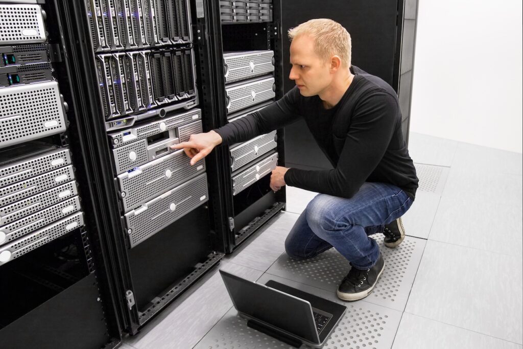 IT professional in server room conducting cybersecurity risk assessment