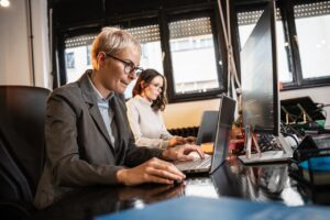 coworkers working in office using information security best practices on computer