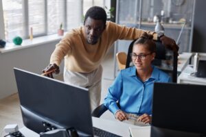 coworkers in office discussing tasks on computer